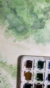 Abstract watercolor art with a palette, highlighting various green shades and textures.