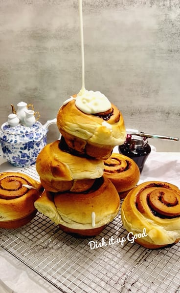 3 cinnamon rolls stacked with a dollop of frosting cream on top.
