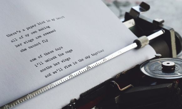Close-up of a vintage typewriter printing a heartfelt poem on paper.