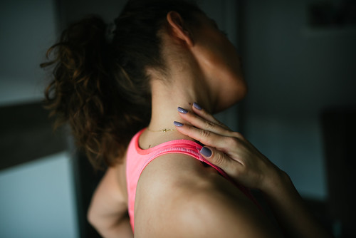 Sporty woman holding her neck in pain closeup.