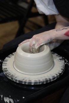 An artist molds a clay pot on a pottery wheel, showcasing the pottery process.