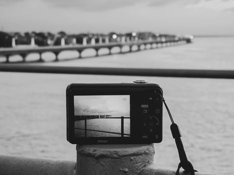 A bridge captured in black and white through a camera screen overlooking water.