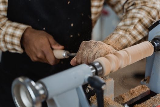 Skilled artisan working with a lathe, carving wood with precision in a workshop.