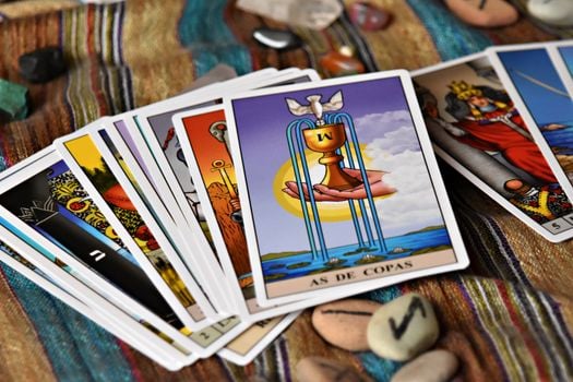 A set of tarot cards spread on a colorful fabric with crystal stones, reflecting mysticism.