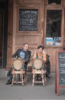A lively Parisian cafe with patrons enjoying outdoor seating in a bustling urban setting.