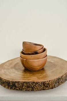 Minimalist still life of wooden bowls stacked on a slice of wood, emphasizing Scandinavian design.