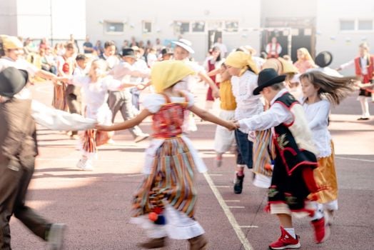 Children in traditional costumes dancing outdoors at a cultural festival in La Orotava, Spain.