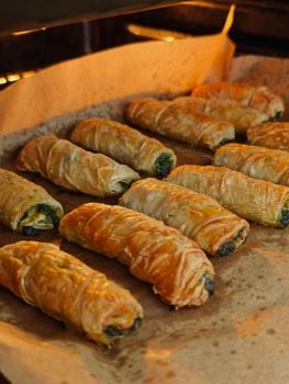 Delicious golden puff pastries with spinach filling freshly baked on a tray.