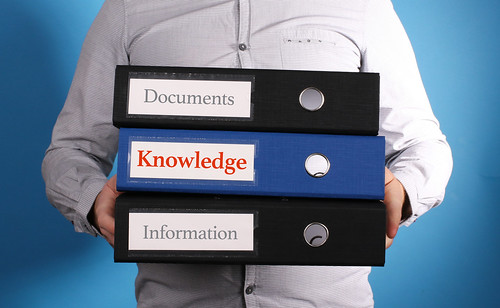 Knowledge - Businessman is carrying a stack of 3 file folders on blue background