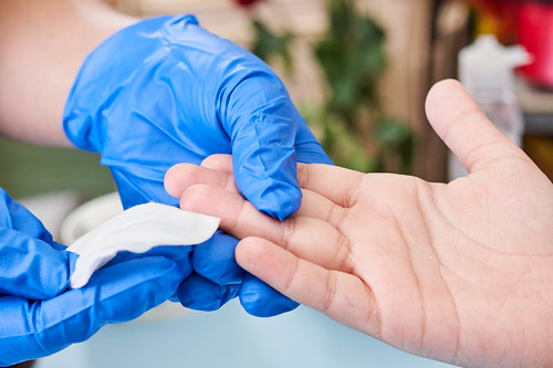 Doctor putting a pad with alcohol in the finger after taking blood test