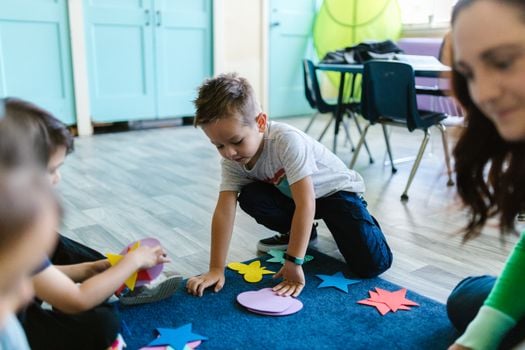 Children playing with colorful shapes in a classroom setting, fostering creativity and learning.