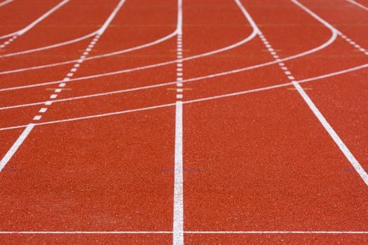 A detailed view of an empty red running track with crisp white lanes, perfect for athletics.