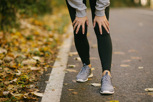 Woman taking a rest from jogging on the side of a road.