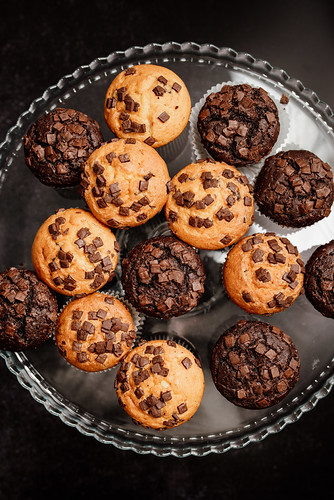 A glass platter holds an assortment of freshly baked chocolate chip muffins
