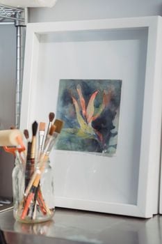 Framed abstract watercolor painting with paintbrushes in a clear jar.