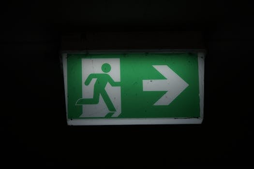 Illuminated green emergency exit sign with an arrow pointing right in a dark setting.