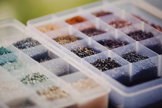 Vibrant beads sorted by color in a plastic container, perfect for crafting and jewelry making.