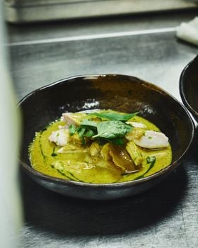Close-up of a flavorful Thai green curry with chicken, garnished with fresh basil leaves.