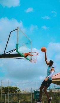 A young man makes an impressive dunk on an outdoor basketball court in Lagos, Nigeria.