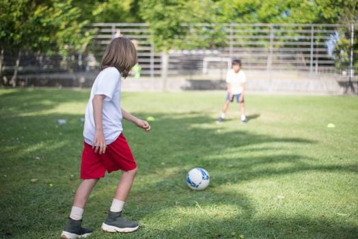 Two children playing soccer outside, enjoying a sunny day in Portugal.