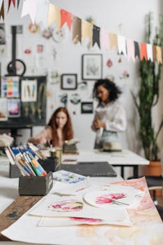 Vibrant art studio featuring watercolor paintings and creative individuals working on new artworks.