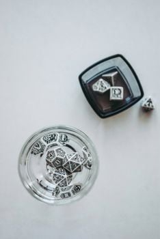 Ornate dice in clear bowls on a white background, showcasing elegant design.