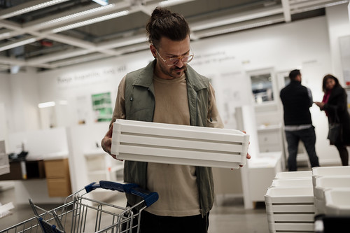 Man examines a white storage box while shopping in a modern home goods store