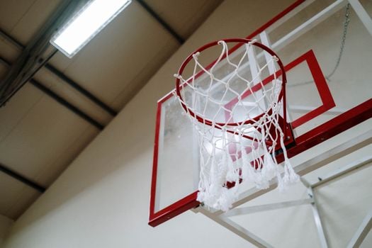A basketball hoop captured from below in an indoor gym. Perfect for sports themes.