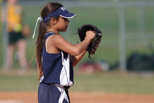 Young girl playing softball, preparing to pitch on a sunny day in the park.