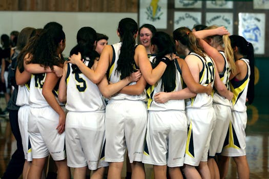 A girls' basketball team huddling before a game, showcasing teamwork and camaraderie.