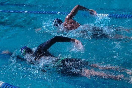 Two swimmers competing in an outdoor pool, showcasing speed and skill.