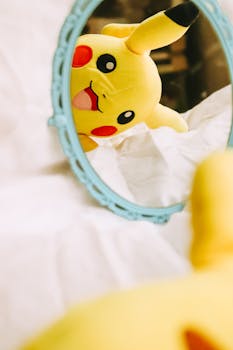 Charming Pikachu plush toy reflected in a stylish blue-framed mirror indoors.