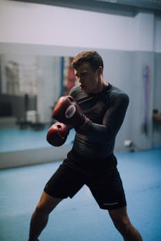 Focused male boxer practicing punches in an indoor boxing gym.