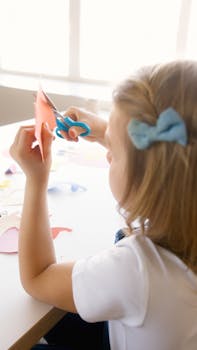 Young girl cutting colored paper, enjoying a creative arts and crafts session indoors.