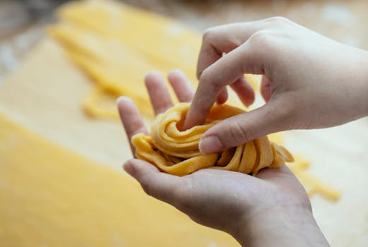 Close-up of hands making fresh homemade pasta from scratch using traditional techniques.