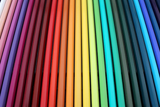 A vibrant and colorful arrangement of colored pencils forming a rainbow spectrum pattern.