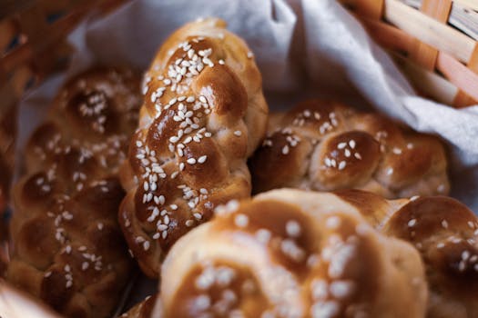 Close-up of freshly baked braided bread topped with sesame seeds in a wicker basket.