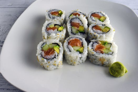 Delicious salmon and avocado sushi rolls neatly plated with a dollop of wasabi, a Japanese culinary delight.