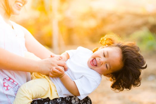 A joyful mother and child laughing together in a sunny outdoor setting, capturing family happiness.