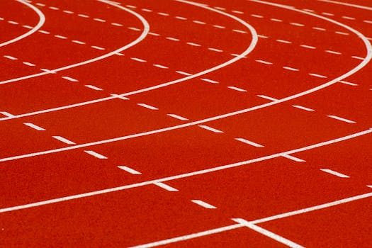 Close-up view of a curved red running track with dashed white lines for athletic sports.