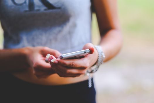 Close-up of a woman texting on a smartphone outdoors, emphasizing mobile connectivity and technology.