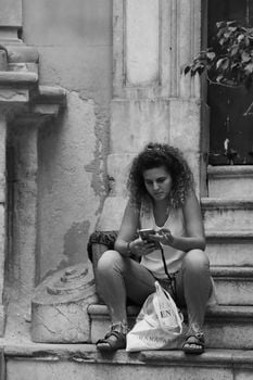 Black and white photo of a woman sitting on steps in Palermo, Sicily, Italy.