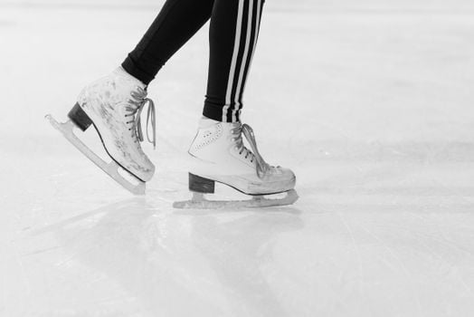 Close-up of ice skater's legs in action on an ice rink in monochrome.