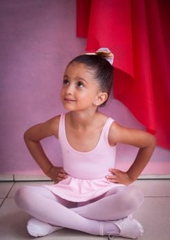 Charming girl dressed for ballet sits in thought, embodying innocence and grace.