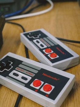 Close-up of classic Nintendo controllers on a wooden table, capturing gaming nostalgia.