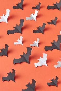 Creative paper bat shapes on orange surface, perfect for Halloween decor.