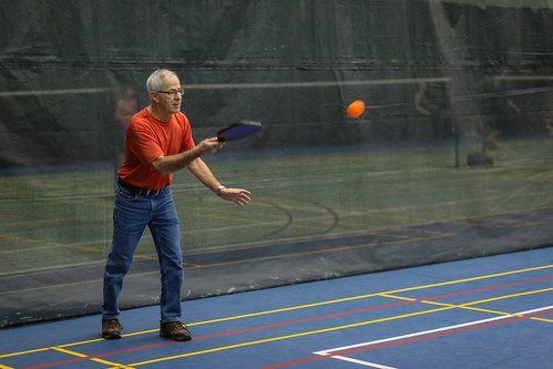 Man playing pickleball on an indoor court.