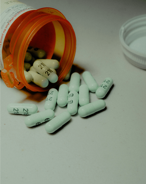 Open prescription pill bottle with capsules spilled onto a flat surface.