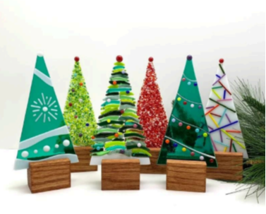 Six fused glass Christmas trees standing in a wood base. 