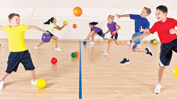 Kids playing dodge ball in a gymnasium. 